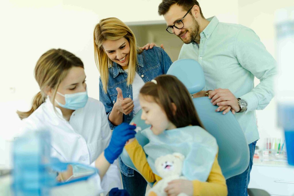 Child sitting with mother and father during a dental checkup.