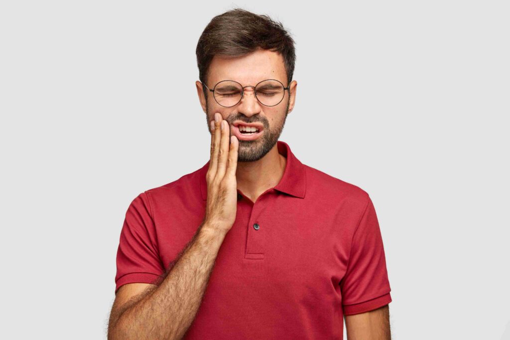 Person experiencing a toothache and facial discomfort.
